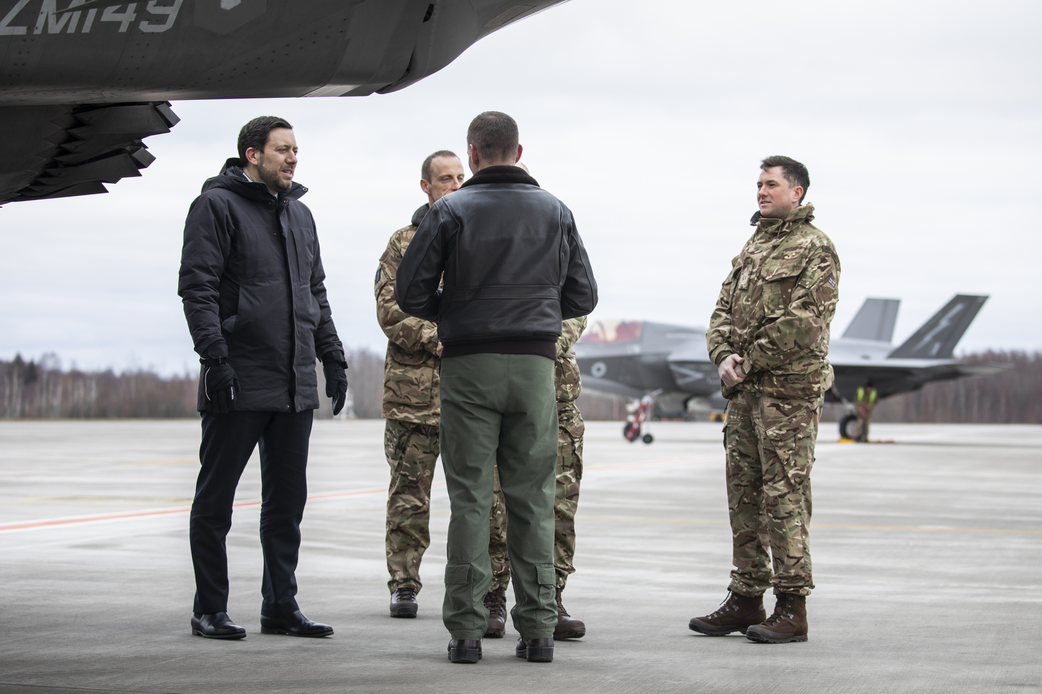 Personnel stand on the airfield before Lightning aircraft.